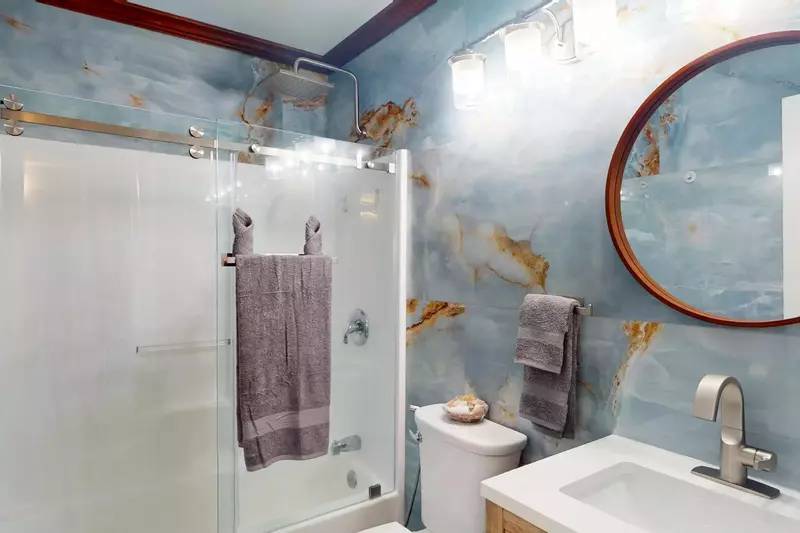 The hall bathroom has beautiful marble walls and a tub/shower combo