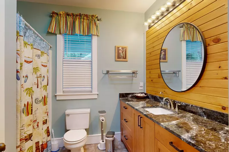 The downstairs full bath has a tub shower combo and a custom wood wall
