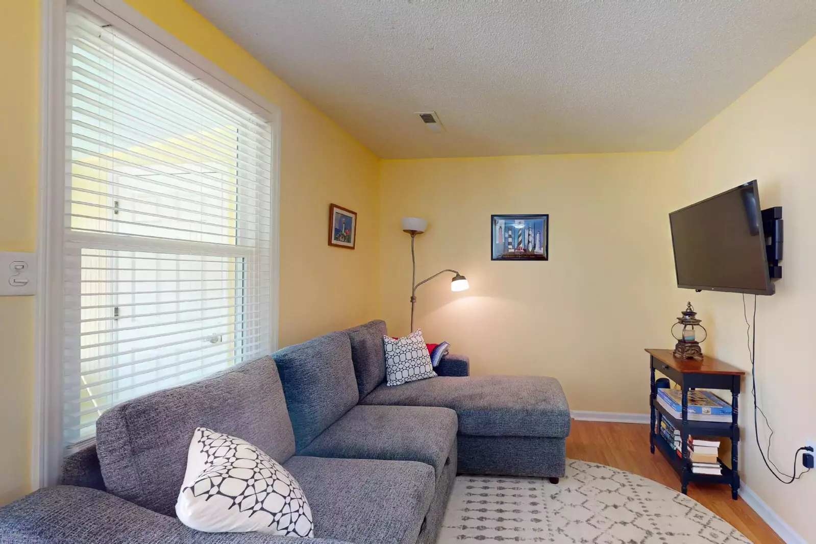 The living room features a couch with a chaise lounge and flat screen tv. The couch also folds out into a bed.