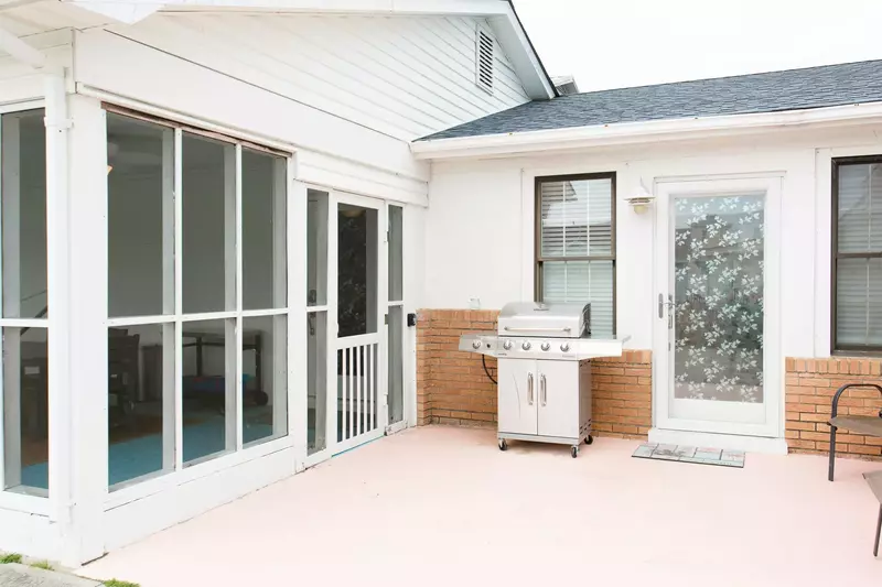 A gas grill and additional seating area is located just off the screened porch