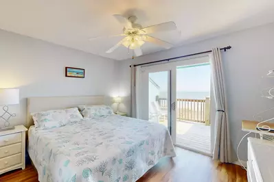 Bright master bedroom with a king bed overlooking the ocean