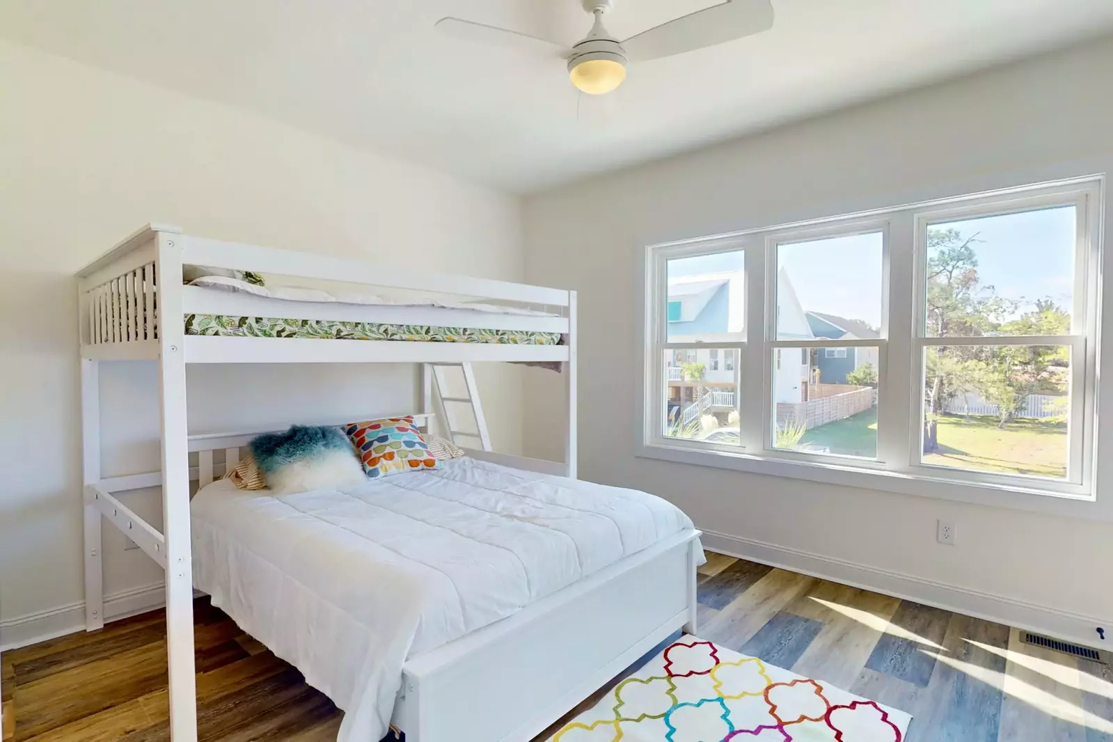 Light and bright bunk room features a full bed over a queen bed