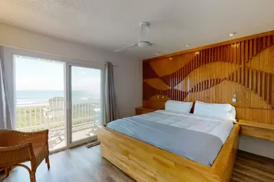 The master bedroom features a custom king bed with a gorgeous full wall headboard and ocean views!