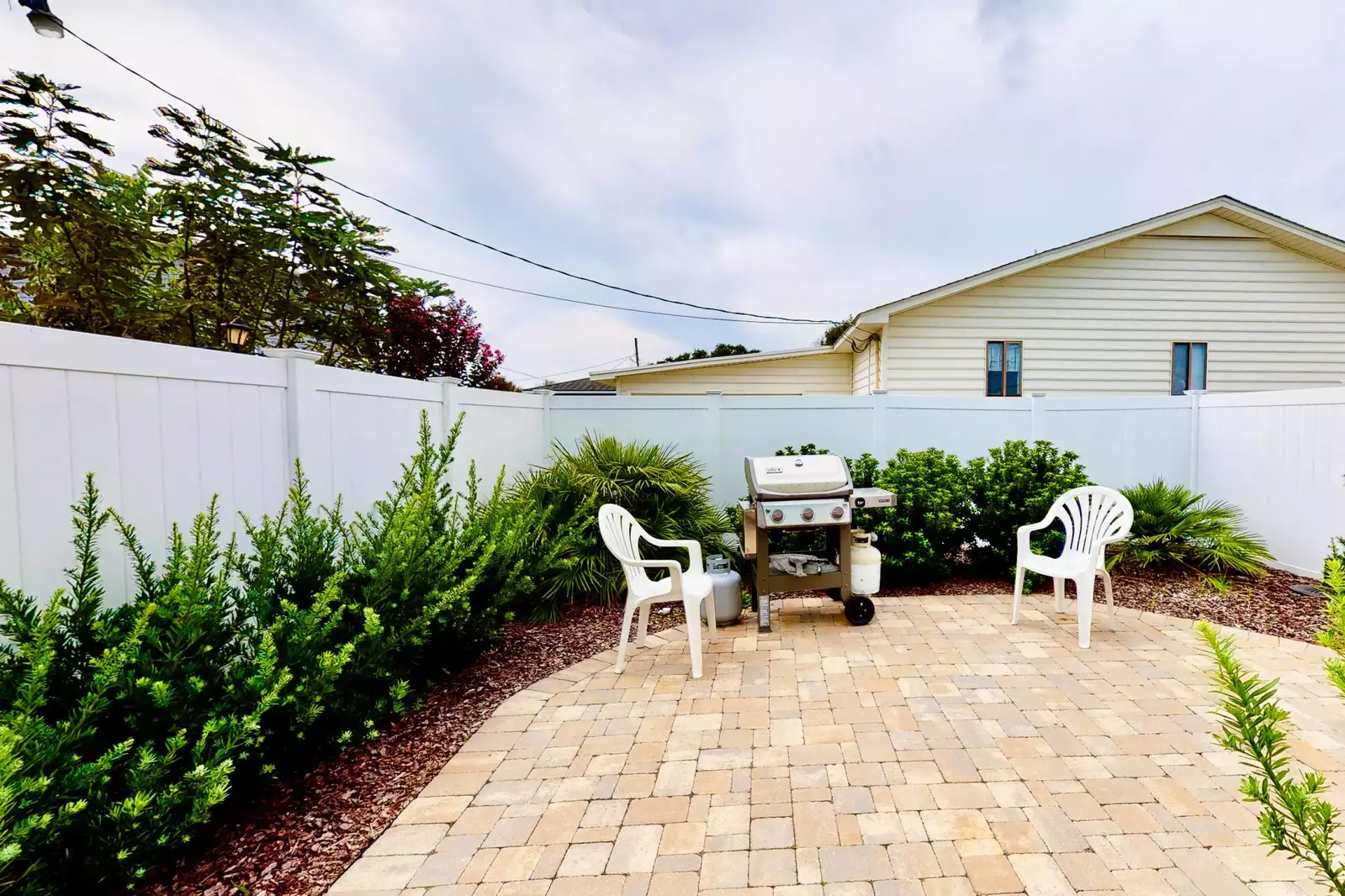 Back yard patio has seating and a gas grill