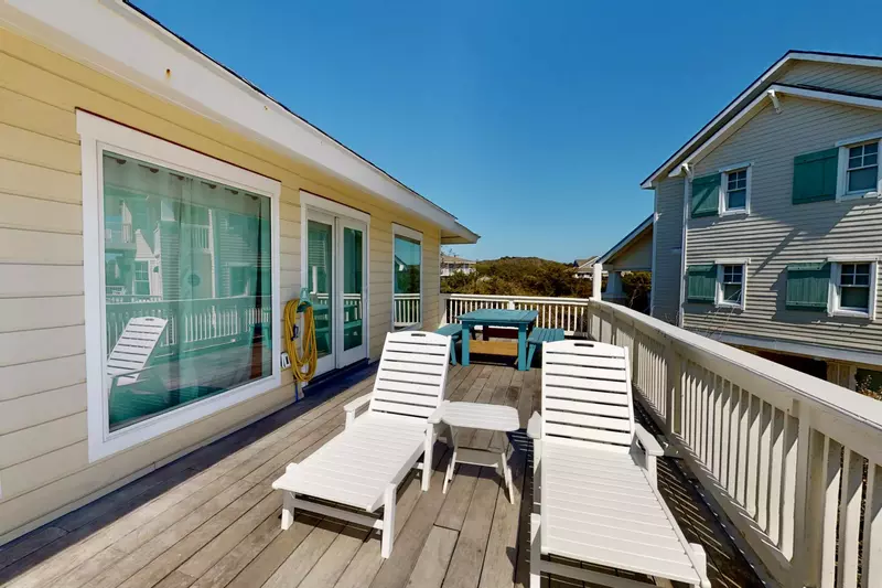 2 nice lounge chairs and a large table with benches on the deck