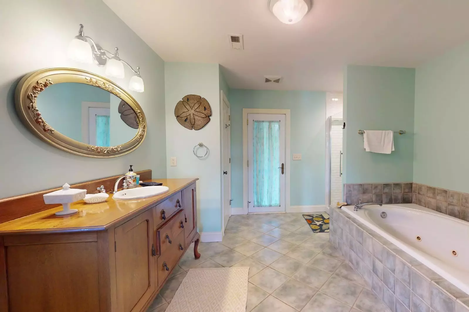 The main master bath has a large open shower stall with rainfall shower head, jacuzzi style tub and access the screened in porch