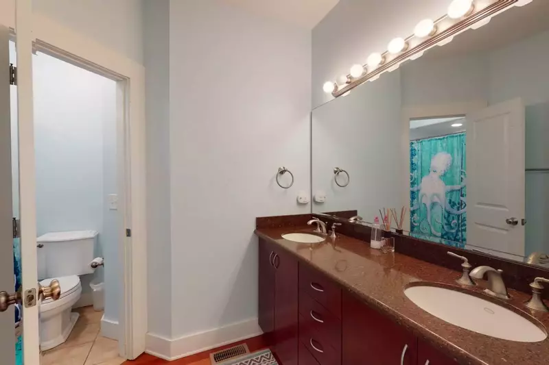 The guest bathroom has double vanity sinks with a separated area for the shower and toilet
