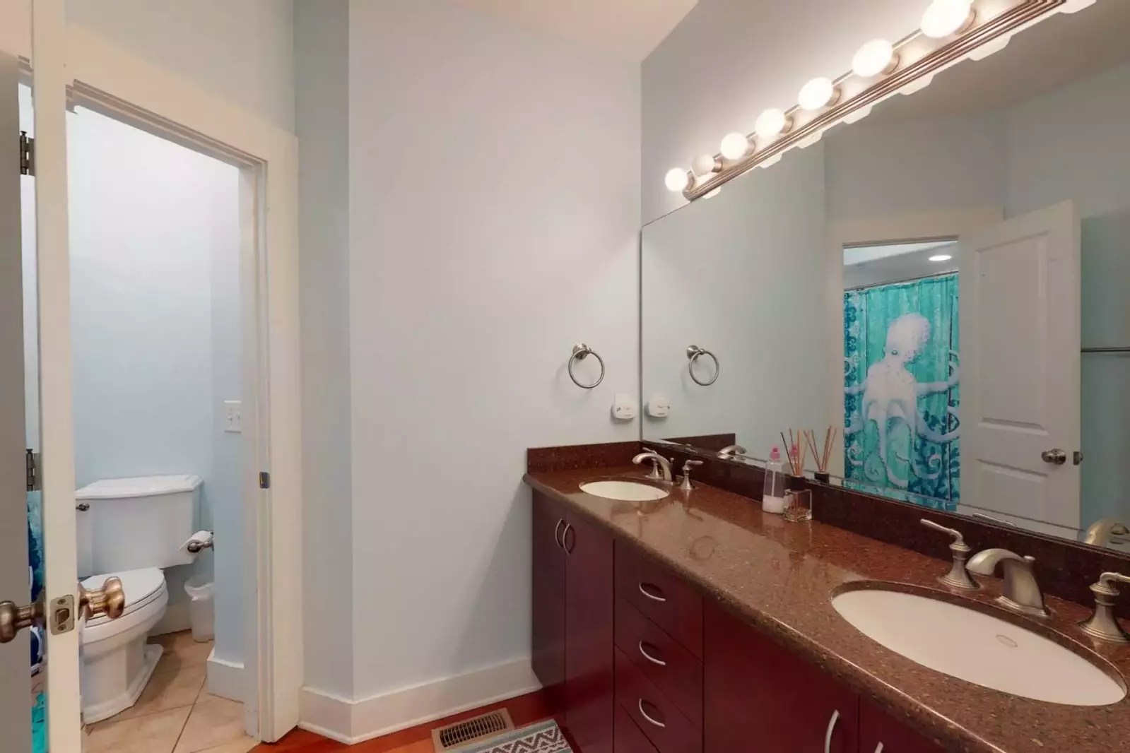 The guest bathroom has double vanity sinks with a separated area for the shower and toilet