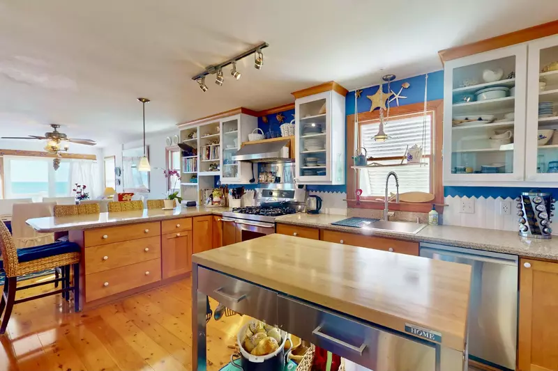 The open kitchen features stainless steel appliances and an island prep station