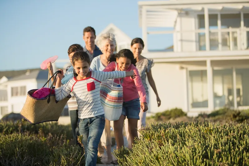 family walking to beach from house
