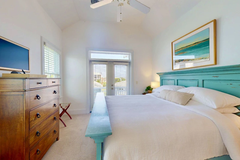 Bedroom 4 has a wall mounted tv and direct access to a top floor deck with peekaboo water views